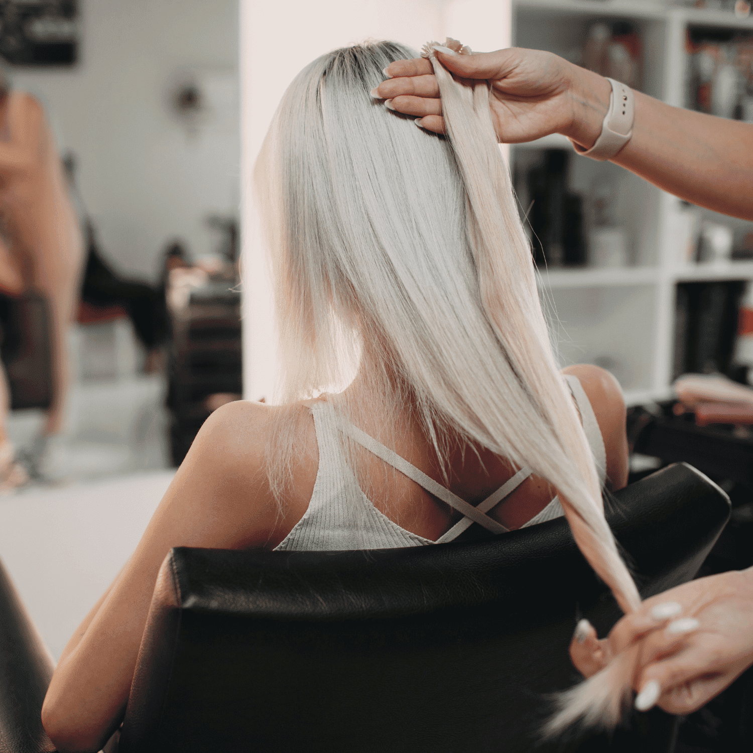 Woman with long blond hair getting styled at a salon.
